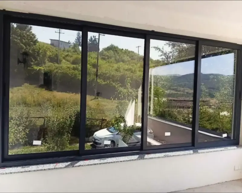 Velike klizne staklene stijene u tamnom okviru, pogled na zelenilo